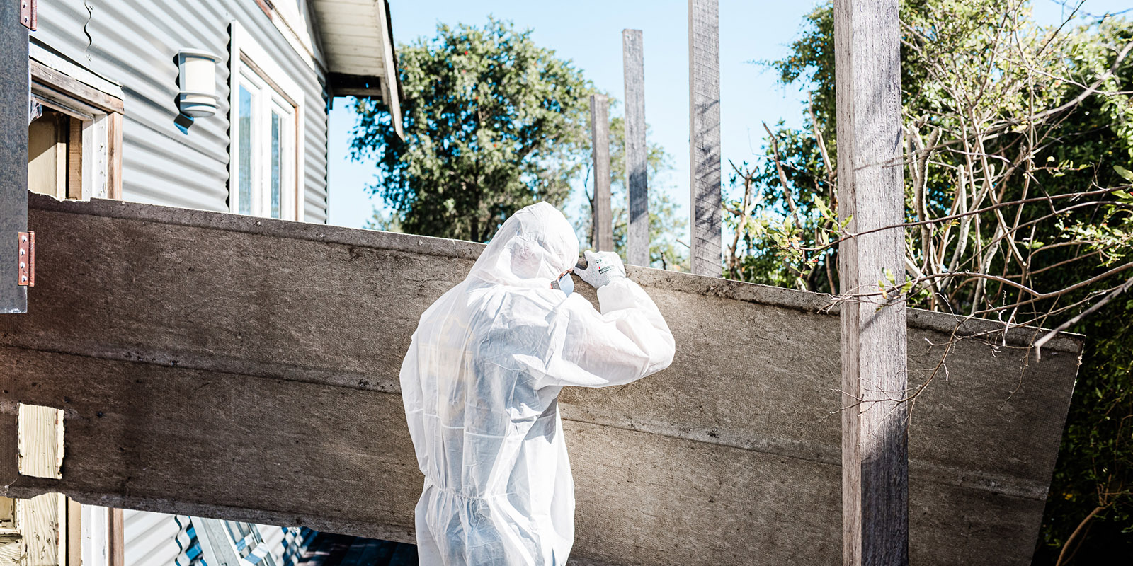 person in hazmat suit working on a house