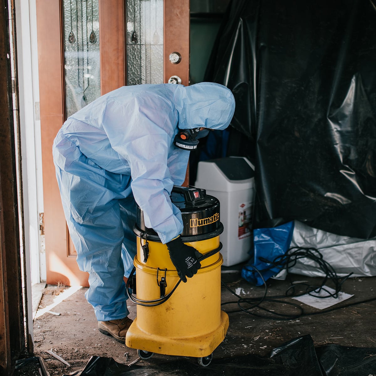 person in hazmat suit working on a house